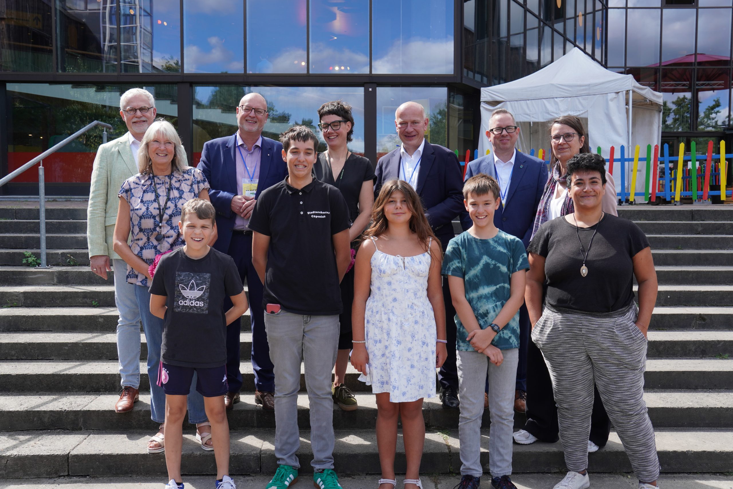 Das Gruppenbild zeigt die Besucher Kai Wegner, Oliver Igel und Falko Liecke zusammen mit FEZ-Mitarbeiter*innen und der FEZitty-Kinderregierung.