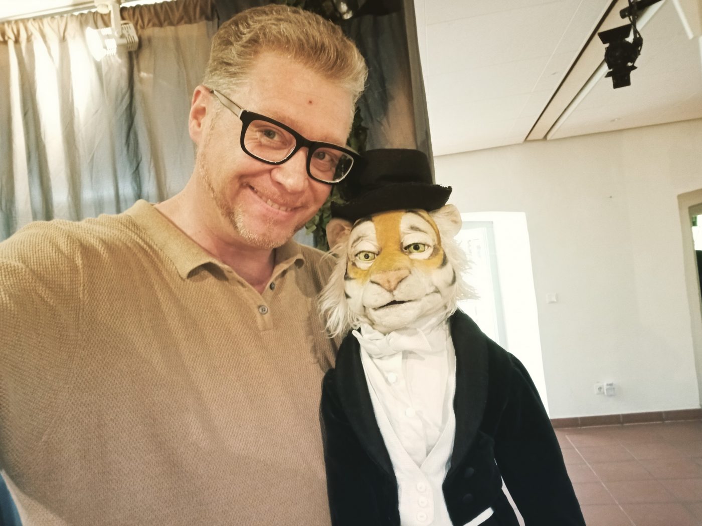 Der künstlerische Leiter des 29. Puppentheaterfests, Stefan Maatz, mit einer Tigerpuppe, die Frack und Zylinder trägt.