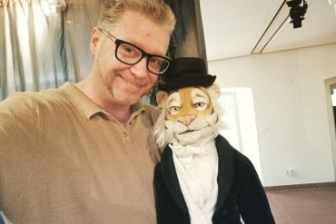 Der künstlerische Leiter des 29. Puppentheaterfests, Stefan Maatz, mit einer Tigerpuppe, die Frack und Zylinder trägt.