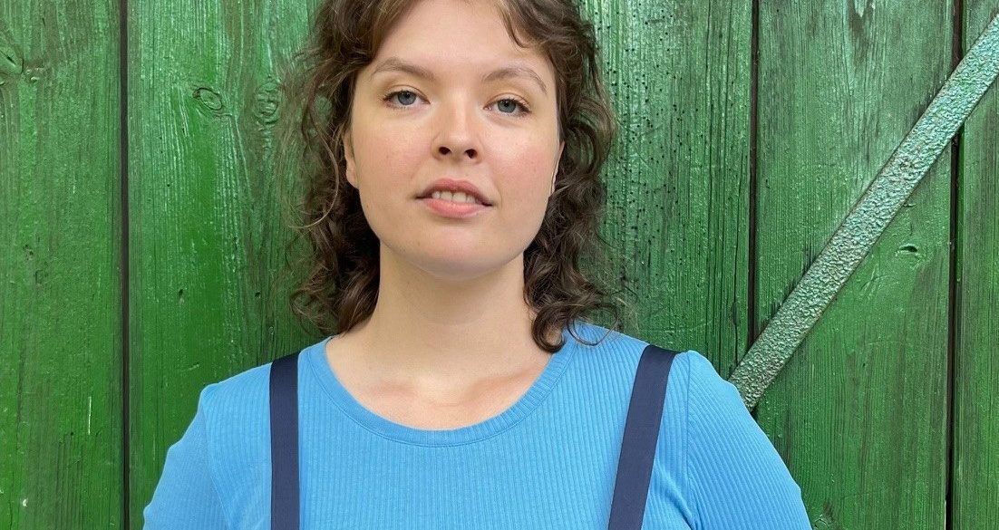 Die Organisatorische Mitarbeiterin der Astrid-Lindgren-Bühne Hannah Walther lehnt an einem grünen Scheunentor.