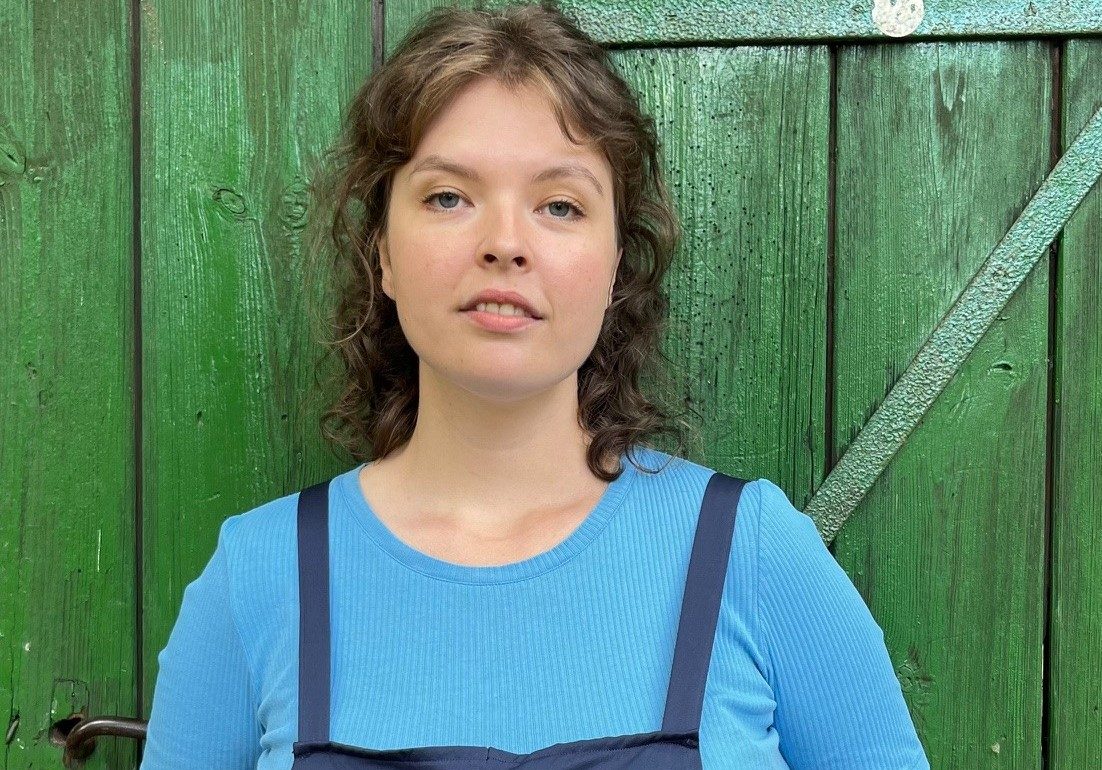 Die Organisatorische Mitarbeiterin der Astrid-Lindgren-Bühne Hannah Walther lehnt an einem grünen Scheunentor.