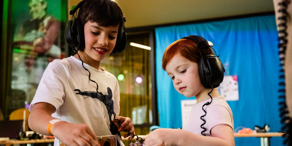 Zwei Kinder drehen die Regler an einem Mischpult.